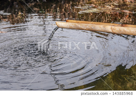 Bamboo Water Spout Pouring into a Reflective Pond Bamboo Water Spout Pouring into a Reflective Pond 143885968