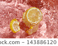 Top view of lemon slices floating in clear rippling water with a pink background. 143886120