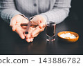 Hands holding a wooden cross beside communion wafers and a dark red beverage, creating a solemn Christian worship scene for faith, prayer, sacred remembrance, and spiritual devotion. 143886782