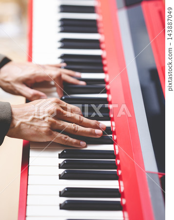 close up male musician hands playing on red piano. music background close up male musician hands playing on red piano. music background 143887049