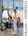 Woman Examining Black Leather Boot in Fashion Store 143889221