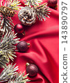 Christmas ornaments and frosted pinecones on red fabric 143890797