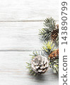 Frosted evergreen branches and pine cones on white wood 143890799