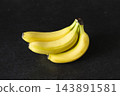 Yellow bananas stand out against a black background. 143891581