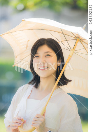一位中年婦女正在撐陽傘。 143892182