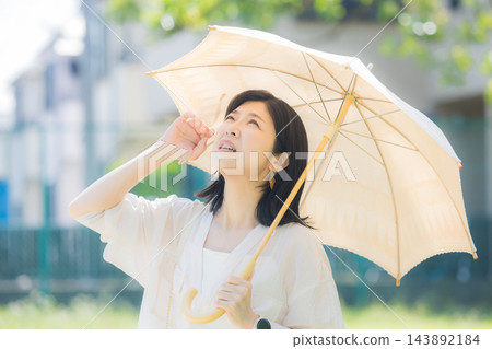 一位中年婦女正在撐陽傘。 一位中年婦女正在撐陽傘。 143892184