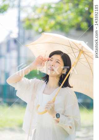 一位中年婦女正在撐陽傘。 一位中年婦女正在撐陽傘。 143892185