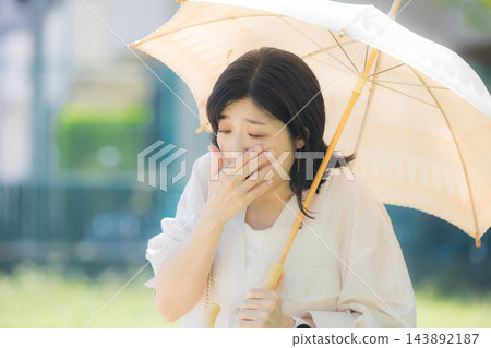 一位中年婦女正在撐陽傘。 一位中年婦女正在撐陽傘。 143892187