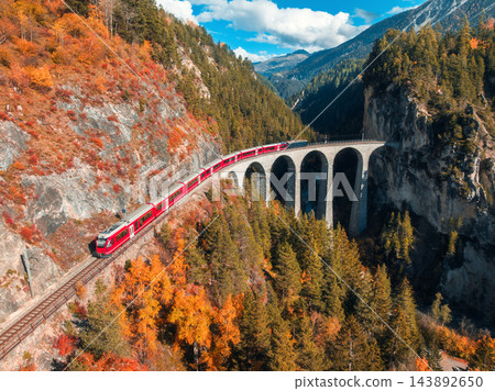 Aerial view of red train on Landwasser viaduct in autumn in Alps Aerial view of red train on Landwasser viaduct in autumn in Alps 143892650