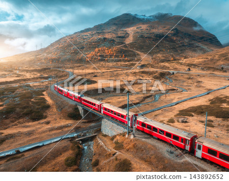 Aerial view of red train is moving through bridges in swiss alps Aerial view of red train is moving through bridges in swiss alps 143892652