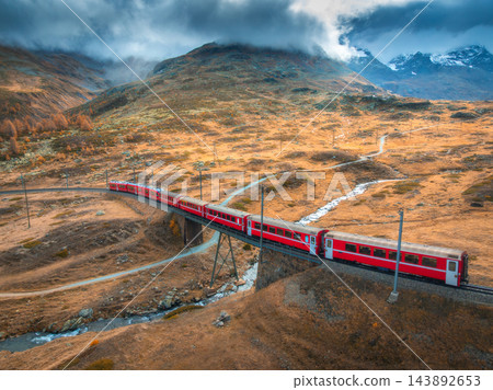 Aerial view of red train is moving through bridges in mountains 143892653