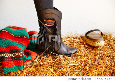 female black boot on stable straw bale female black boot on stable straw bale 143893738
