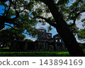 The Atomic Bomb Dome and the blue sky visible beyond the large trees. 143894169