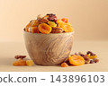 Assorted nuts and dried fruits in wooden bowl on  a beige background. 143896103