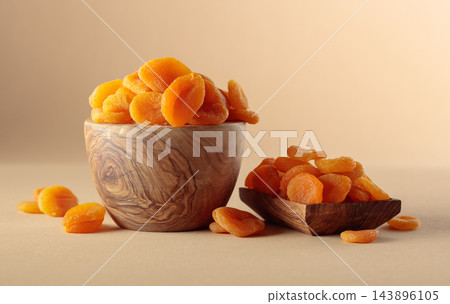Organic dried apricots in wooden bowl on a beige background. Organic dried apricots in wooden bowl on a beige background. 143896105