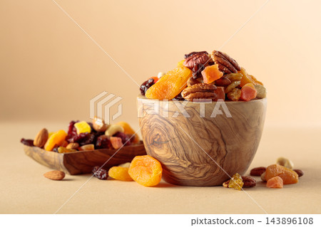 Assorted nuts and dried fruits in wooden bowl on  a beige background. 143896108