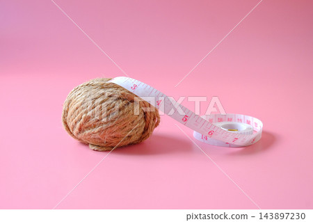 A coil of jute rope with measuring tape on background. 143897230