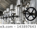Row of large black valve handwheels on insulated industrial pipelines at a processing plant. 143897643