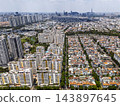 Aerial drone view of Ho Chi Minh City showing the dense urban landscape with high-rise apartments, low-rise residential areas, and Landmark 81 on the horizon. 143897645