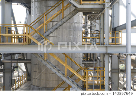 Industrial tank facility featuring complex steel structures and stairs with yellow safety handrails Industrial tank facility featuring complex steel structures and stairs with yellow safety handrails 143897649
