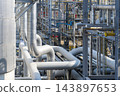 Close-up of a large-scale, intricately designed pipe rack system and metal piping structures inside a gas plant. 143897653