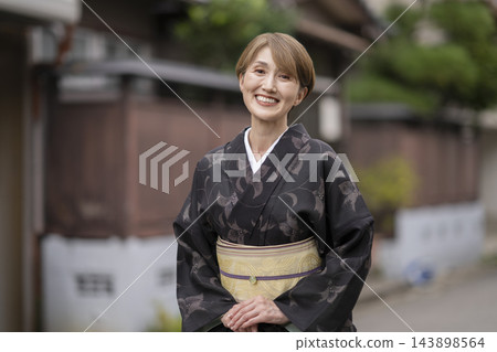 一位五十多歲的女性身穿越後夏季和服，微笑著直視鏡頭，她的肖像照。 143898564
