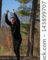 Young man using resistance band for strength training in forest 143899707