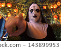 Spooky nun point finger by hanging pumpkin lantern light. halloween 2026 143899953