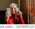 Joyful mature woman holding money 143900110