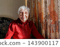 Portrait of Elderly woman looking out window, Grandmother smiling 143900117