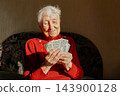 Joyful mature woman holding money 143900128