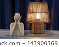 Abstract sculpture and wooden lamp illuminate a minimalist interior table 143900369