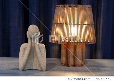 Abstract sculpture and wooden lamp illuminate a minimalist interior table Abstract sculpture and wooden lamp illuminate a minimalist interior table 143900369