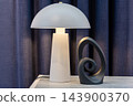 Modern interior lighting with a white lamp illuminating sculpture on a wooden table 143900370