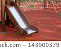 Playground slide stands empty among autumn leaves in an outdoor park 143900379