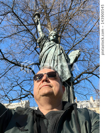 Man posing in front of a Statue of Liberty replica in Paris, France, on a sunny day. Travel, tourism and sightseeing concept. High quality photo Man posing in front of a Statue of Liberty replica in Paris, France, on a sunny day. Travel, tourism and sightseeing concept. High quality photo 143900545