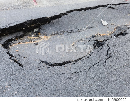 High angle shot of a large dangerous pothole and cracked collapsed asphalt on a city street pavement High angle shot of a large dangerous pothole and cracked collapsed asphalt on a city street pavement 143900621