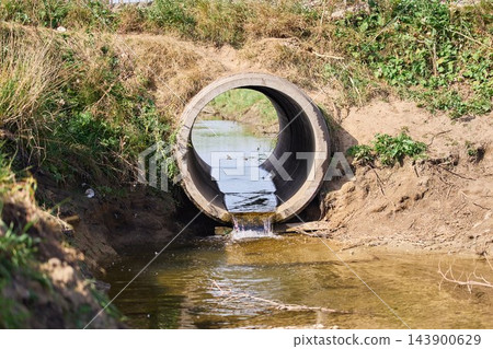 Concrete drainage culvert pipe discharging water into a stream in a rural landscape Concrete drainage culvert pipe discharging water into a stream in a rural landscape 143900629