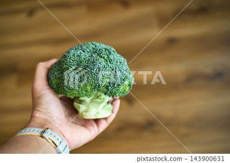 Man Holding Whole Green Broccoli Florets Indoors Man Holding Whole Green Broccoli Florets Indoors 143900631