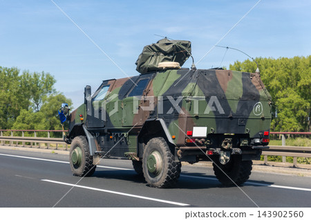 German military truck camouflage drives along autobahn green forest landscape during summer daylight. Tactical transport vehicle logistic defense mobility convoy movement European road infrastructure German military truck camouflage drives along autobahn green forest landscape during summer daylight. Tactical transport vehicle logistic defense mobility convoy movement European road infrastructure 143902560