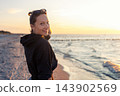 Portrait young adult woman dreamy looking sunset horizon on sandy beach shore warm evening sunset light. Scenic wellbeing concept mindfulness balance hope emotional recovery mental health sea 143902569
