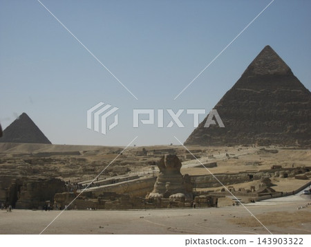 展現埃及吉薩大獅身人面像的壯麗全景，背景是胡夫金字塔和門卡烏拉金字塔。 143903322