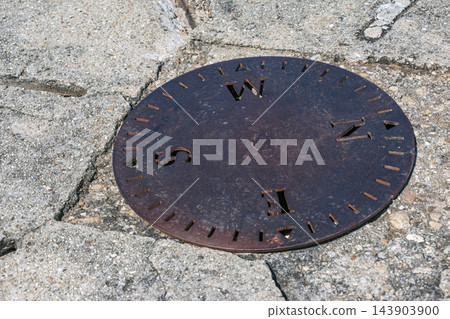 Nitra, Slovakia - May 29, 2024: Round metal compass marker set in cracked stone Nitra, Slovakia - May 29, 2024: Round metal compass marker set in cracked stone 143903900