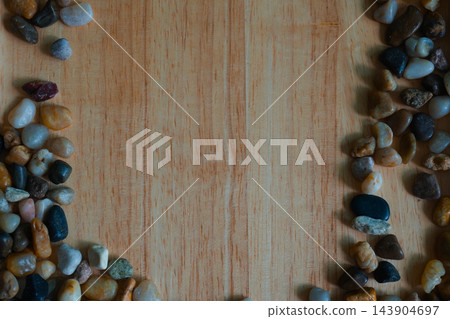 Colorful polished river pebbles arranged at the corner of wooden background Colorful polished river pebbles arranged at the corner of wooden background 143904697