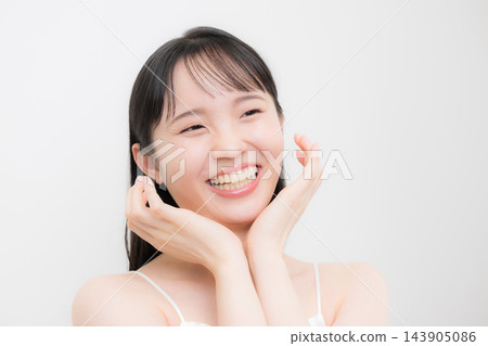 一位年輕女子，可能是十幾歲或二十出頭，雙手托著下巴和臉頰，以白色為背景，抬頭露出美麗的笑容。 143905086