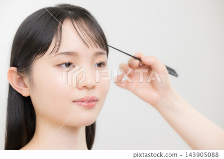 一位髮型師和化妝師正在梳理一位年輕日本女性的瀏海,示範如何打理她的瀏海以及如何打理她的頭髮。 一位髮型師和化妝師正在梳理一位年輕日本女性的瀏海,示範如何打理她的瀏海以及如何打理她的頭髮。 143905088