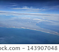 Long coastline below layered sky during flight 143907048