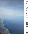 Curved coastal bay beneath translucent haze 143907051