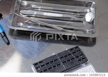 Orthodontic brackets and dental instruments arranged in a stainless steel tray for braces treatment preparation, clinic education, and professional dentistry communication. Orthodontic brackets and dental instruments arranged in a stainless steel tray for braces treatment preparation, clinic education, and professional dentistry communication. 143907213
