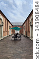 A retro-modern streetscape of red brick buildings and a view of a cafe terrace. 143908484